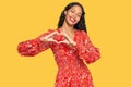 Young african american girl wearing summer dress smiling in love showing heart symbol and shape with hands Royalty Free Stock Photo