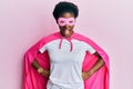 Young african american girl wearing super hero costume and medical mask sticking tongue out happy with funny expression