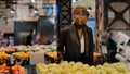 Young african american girl woman shopper consumer in medical mask in store chooses products apples fruits buying food Royalty Free Stock Photo