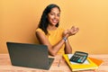 Young african american girl working at the office with laptop and calculator pointing aside with hands open palms showing copy Royalty Free Stock Photo