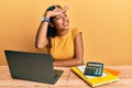 Young african american girl working at the office with laptop and calculator very happy and smiling looking far away with hand Royalty Free Stock Photo