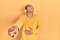 Young african american guy listening to music using headphones laughing at you, pointing finger to the camera with hand over body, Royalty Free Stock Photo