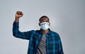 Young african american guy wearing protective mask with inscription BLM looking at camera, while posing with raised fist