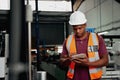 Young african american industrial worker working on digital tablet in the factory - you black male checking modern