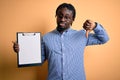 Young african american inspector man wearing glasses holding clipboard checklist with angry face, negative sign showing dislike