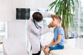 Young African American male doctor examines the eyes of his patient little boy, sitting on the couch in medical office Royalty Free Stock Photo