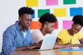 Young african american male student at computer with group of students