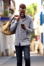 Young african american male traveler walking outside and using mobile phone Royalty Free Stock Photo