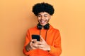 Young african american man with afro hair using smartphone smiling and laughing hard out loud because funny crazy joke Royalty Free Stock Photo
