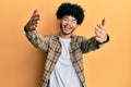 Young african american man with afro hair wearing casual clothes looking at the camera smiling with open arms for hug Royalty Free Stock Photo