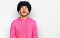 Young african american man with afro hair wearing casual pink sweatshirt angry and mad screaming frustrated and furious, shouting Royalty Free Stock Photo