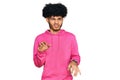 Young african american man with afro hair wearing casual pink sweatshirt disgusted expression, displeased and fearful doing Royalty Free Stock Photo