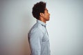 Young african american man with afro hair wearing grey shirt over isolated white background looking to side, relax profile pose Royalty Free Stock Photo