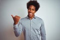 Young african american man with afro hair wearing grey shirt over isolated white background smiling with happy face looking and Royalty Free Stock Photo