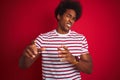 Young african american man with afro hair wearing striped t-shirt over isolated red background disgusted expression, displeased Royalty Free Stock Photo