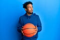 Young african american man with beard holding basketball ball smiling looking to the side and staring away thinking Royalty Free Stock Photo