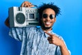 Young african american man with beard holding boombox, listening to music smiling happy pointing with hand and finger Royalty Free Stock Photo