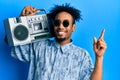 Young african american man with beard holding boombox, listening to music smiling happy pointing with hand and finger to the side Royalty Free Stock Photo