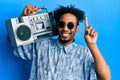 Young african american man with beard holding boombox, listening to music smiling with an idea or question pointing finger with Royalty Free Stock Photo