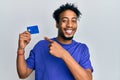 Young african american man with beard holding credit card smiling happy pointing with hand and finger Royalty Free Stock Photo