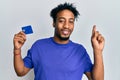 Young african american man with beard holding credit card smiling happy pointing with hand and finger to the side Royalty Free Stock Photo