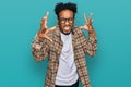 Young african american man with beard wearing casual clothes and glasses shouting frustrated with rage, hands trying to strangle, Royalty Free Stock Photo