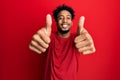 Young african american man with beard wearing casual red t shirt approving doing positive gesture with hand, thumbs up smiling and Royalty Free Stock Photo