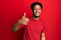 Young african american man with beard wearing casual red t shirt doing happy thumbs up gesture with hand Royalty Free Stock Photo