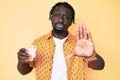 Young african american man with braids holding glass of milk with open hand doing stop sign with serious and confident expression,