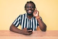 Young african american man with braids using smartphone sitting on the table surprised with an idea or question pointing finger Royalty Free Stock Photo