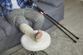 Young African American man with a broken leg sitting with crutches on the sofa at home Royalty Free Stock Photo
