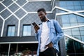 Young African American man in city texting cell phone walking Royalty Free Stock Photo