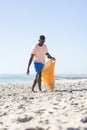 Young African American man collects trash on a sunny beach Royalty Free Stock Photo