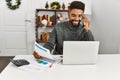 Young african american man controlling economy using laptop and talking on the smartphone at home Royalty Free Stock Photo
