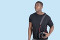 Young African American man with digital camera looking up over blue background Royalty Free Stock Photo