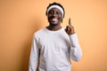 Young african american man doing sport wearing sportswer over isolated yellow background pointing finger up with successful idea Royalty Free Stock Photo