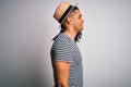 Young african american man with dreadlocks on vacation wearing striped t-shirt and hat looking to side, relax profile pose with Royalty Free Stock Photo