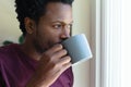 Young african american man drinking coffee from mug while looking away at home Royalty Free Stock Photo