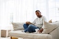 Young african american man in earphone reading book near notebook during self-education at home Royalty Free Stock Photo