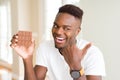 Young african american man eating chocolate bar pointing and showing with thumb up to the side with happy face smiling Royalty Free Stock Photo