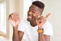 Young african american man eating chocolate bar very happy pointing with hand and finger to the side Royalty Free Stock Photo