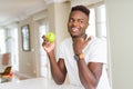 Young african american man eating fresh green apple pointing and showing with thumb up to the side with happy face smiling Royalty Free Stock Photo