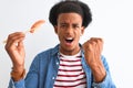 Young african american man eating nigiri using chopsticks over isolated white background annoyed and frustrated shouting with