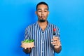 Young african american man eating salad making fish face with mouth and squinting eyes, crazy and comical Royalty Free Stock Photo