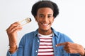 Young african american man eating sushi using chopsticks over isolated white background with surprise face pointing finger to