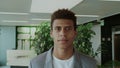 Handsome black man in suit. Young African-American man in elegant suit standing in modern office and smiling happily at