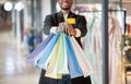 Young african american man expressing success, showing to camera of colored shopping bags and credit card