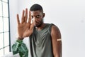 Young african american man getting vaccine showing arm with band aid with open hand doing stop sign with serious and confident Royalty Free Stock Photo