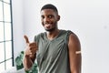 Young african american man getting vaccine showing arm with band aid smiling happy and positive, thumb up doing excellent and Royalty Free Stock Photo