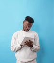 A young African-American man with glasses writes down information in a notebook on a blue background Royalty Free Stock Photo